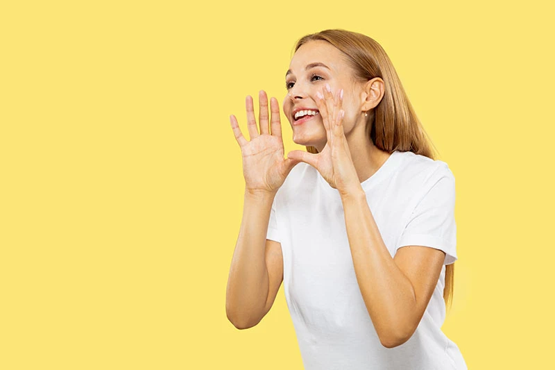 Une femme parle les mains en parabole autour de sa bouche. Image by master1305 on Freepik 